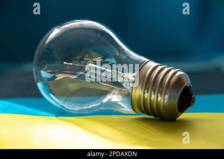An incandescent light bulb lies on the flags of Ukraine close-up in the sunlight Stock Photo