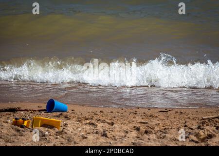 A blue pail and other toys in the sand at the beach Stock Photo