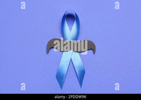 Awareness ribbon with paper mustache on blue background Stock Photo