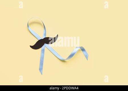 Light blue awareness ribbon with black paper mustache on color background Stock Photo