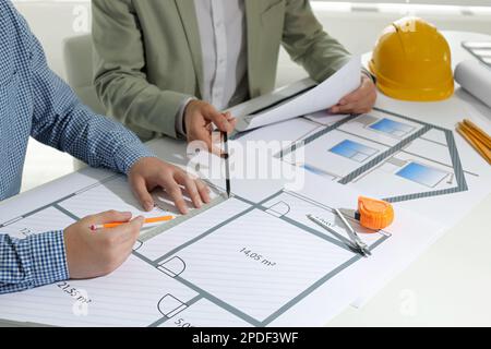 Architects working with construction drawings at table in office, closeup Stock Photo