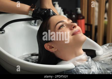 Hairdresser rinsing out dye from woman's hair in beauty salon Stock Photo