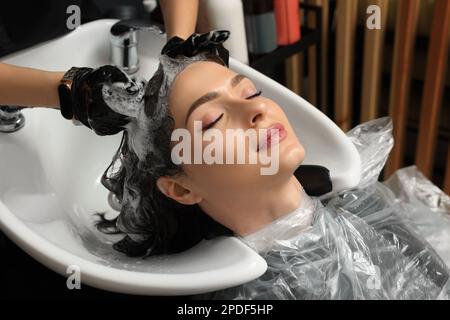 Hairdresser rinsing out dye from woman's hair in beauty salon Stock Photo