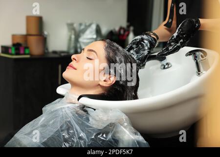 Hairdresser rinsing out dye from woman's hair in beauty salon Stock Photo