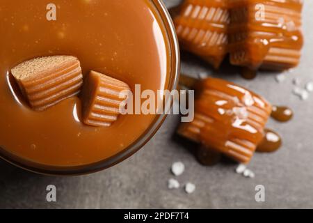 Tasty salted caramel with candies in glass bowl on grey table, top view Stock Photo