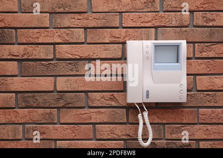 Modern intercom system with handset on red brick wall, space for text Stock Photo