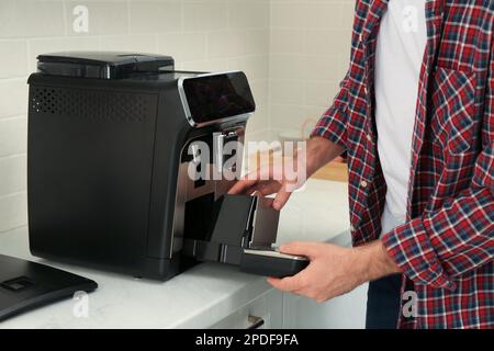 Man fixing coffee machine at table indoors, closeup Stock Photo