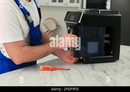Repairman fixing coffee machine at table indoors, closeup Stock Photo