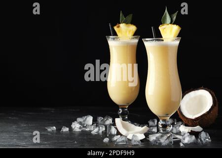 Tasty Pina Colada cocktails on dark table, space for text Stock Photo