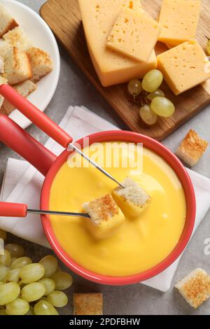 Flat lay composition with pot of tasty cheese fondue on grey table Stock Photo