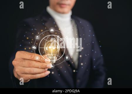 Businessman holding light bulb with globe icons. environmental conservation and modernization of technology and natural resources to reduce pollution Stock Photo