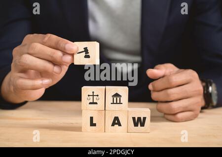 Man holding wooden cube with law icon. Law business and justice banner, scale and fairness. copy space Stock Photo