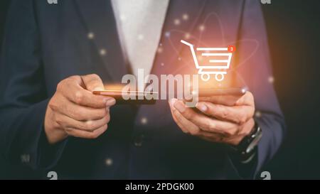 Male hand using smartphone making an online payment by credit card. Shop online with a cart Stock Photo