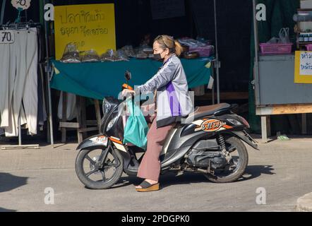 SAMUT PRAKAN, THAILAND, FEB 13 2023, A woman rides a motorcycle at marketplace Stock Photo