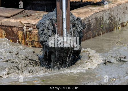 Dredging the bottom of water area, view of the bucket of the floating excavator full of mud Stock Photo