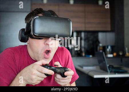 Feeling excited and amazed. Young man wearing VR goggles while playing video games in virtual world. Stock Photo