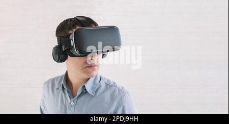 Astonished caucasian male in blue t-shirt, using oculus rift headset, experiencing virtual reality while playing video game, looking joyful, white wal Stock Photo