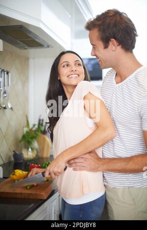 Cooking as a couple. A happy young couple preparing food in the kitchen. Stock Photo
