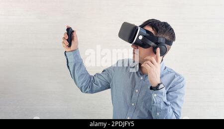 vr for phone and mobile gaming. man wearing virtual reality headset or goggles on white background, looking around, excited by participation effect, w Stock Photo