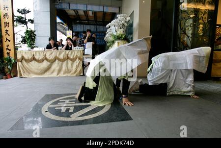 Draped in traditional Taiwanese funeral hood, a professional mourner of ...