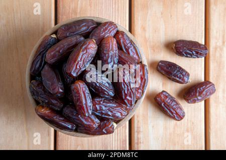 Date fruits in wooden bowl,on wooden table Stock Photo