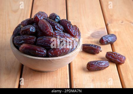 Date fruits in wooden bowl,on wooden table Stock Photo
