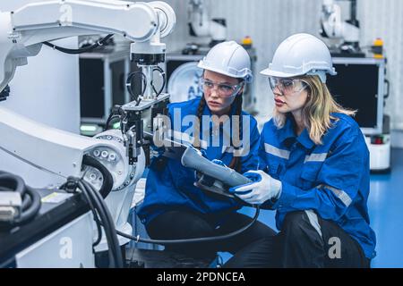 smart engineer woman team worker working together service robot arm in automation factory industry Stock Photo