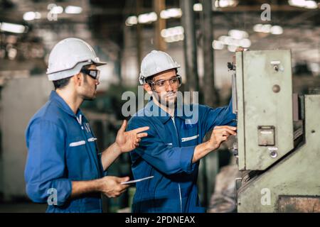 Engineer supervisor professional worker working team together training operate machine in dirty heavy metal industry. Stock Photo