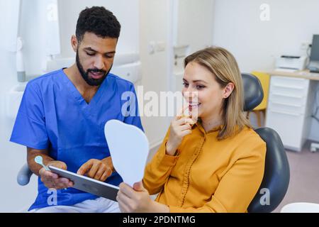 Young woman having consultation with multiracial dentist. Stock Photo
