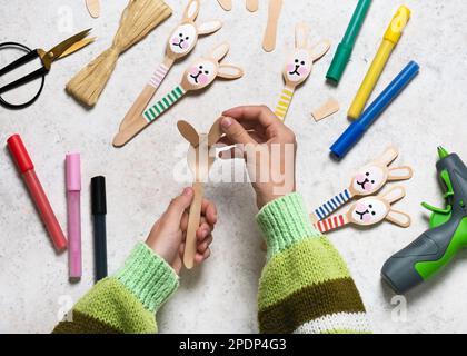 Step 9. Attach rabbit ears to wooden spoon. Making cute bunny decor for Easter with kids. Flat lay. Stock Photo
