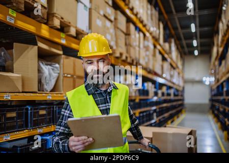 Male warehouse worker dragging a pallet truck Stock Photo - Alamy