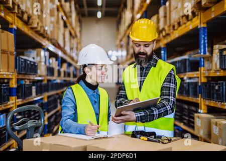 Warehouse workers checking stuff in warehouse with digital system in tablet, holding solar panel. Stock Photo