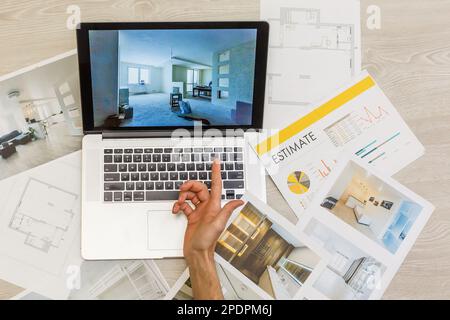 Decorator's hands with ruler on project drawings. Laptop, color swatches and tools on work table Stock Photo