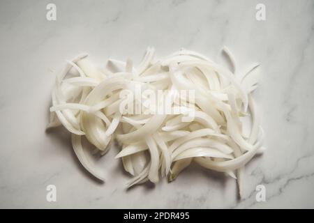 Julienne cuted onions on white marble background. Photo show how does julienne sliced or pole to pole to root to stem or half rings onions look like Stock Photo