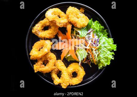 Fried squid or calamari in batter on a black plate close up top view Stock Photo