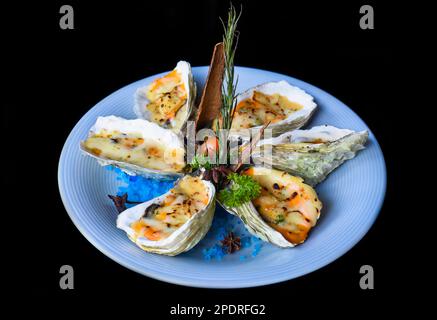 Oysters baked with 3 cheeses on white plate close up Stock Photo