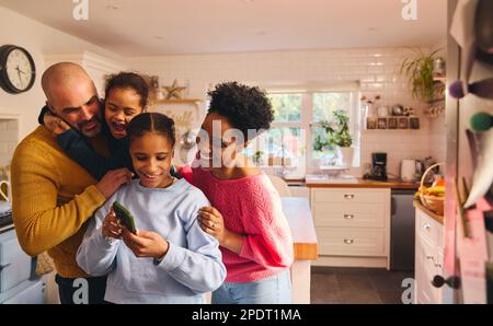Teen girl looking at selfie on phone with family Stock Photo