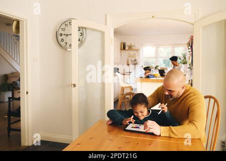 Multiracial father and son with Down syndrome using digital tablet Stock Photo