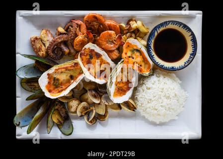 Sautéed seafood on white plate close up isolated on black background top view Stock Photo