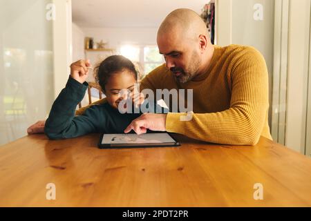 Multiracial father and son with Down syndrome using digital tablet for homework Stock Photo