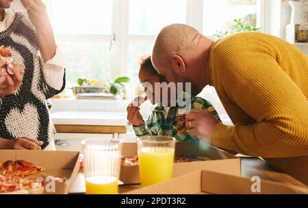 Boy with Down syndrome enjoying takeaway pizza with family Stock Photo