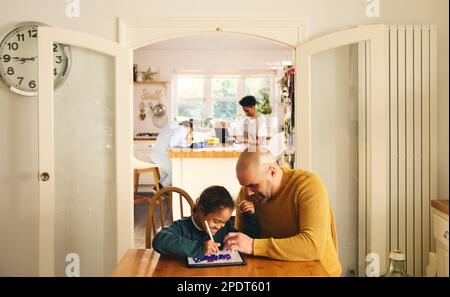Multiracial family at home with father and son with Down syndrome using digital tablet Stock Photo