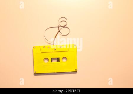 Yellow audio cassette and modern wireless headphones on a pink background. Comparison of old and new technologies. Listening to music, music lovers. T Stock Photo