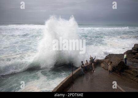 Onlookers watching Atlantic Ocean wave breaking over seafront wall, Azenhas do Mar, Lisbon Region, Portugal, Europe Stock Photo