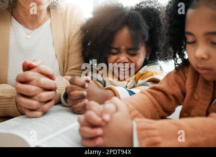 Bible, prayer or hands of grandmother with kids or siblings for worship, support or hope in Christianity. Children education, praying or old woman Stock Photo