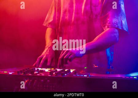 Hands of a DJ creating and regulating music on dj console mixer at club concert Stock Photo