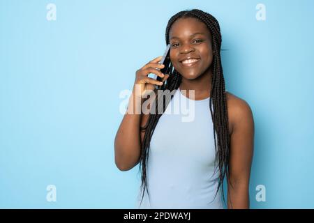 Portrait of young cheerful black lady using Smartphone For Messaging With Friends, Happy African American Lady Texting On Cellphone while standing Ove Stock Photo