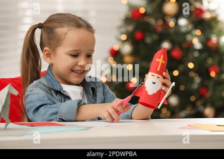 Cute little girl making paper Saint Nicholas toy at home Stock Photo