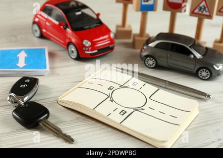 Composition with workbook for driving lessons and toy cars on white wooden background. Passing license exam Stock Photo