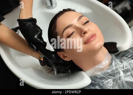 Hairdresser rinsing out dye from woman's hair in beauty salon Stock Photo